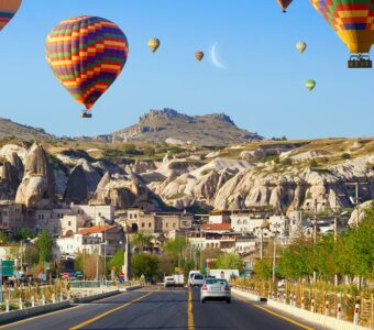Hot air balloons fly over the Goreme road at sunrise in Cappadocia